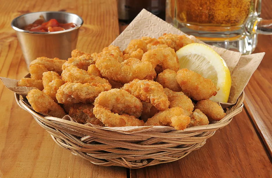 Popcorn shrimp and beer a bowl of food sitting on a table