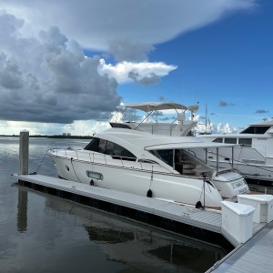 White yacht docked at marina with cloudy sky in the background.