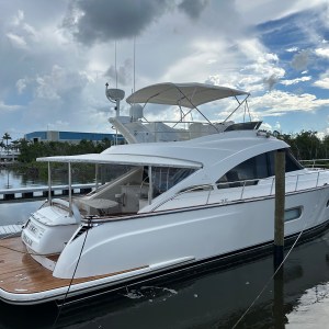 A white luxury yacht docked at a marina under a cloudy sky.