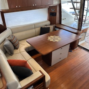 Cozy yacht interior with cream leather sofa, wooden table, and decorative pillows.
