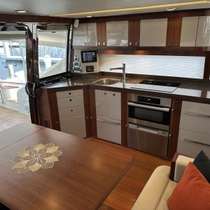 Modern yacht kitchen with wood cabinets, appliances, sink, and dining area with flower pattern on table.