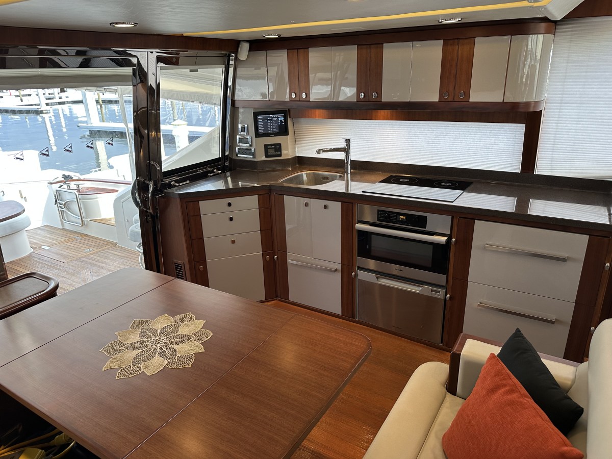 Modern yacht kitchen with wood cabinets, appliances, sink, and dining area with flower pattern on table.