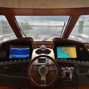 View from a boat cockpit with steering wheel and navigation screens.