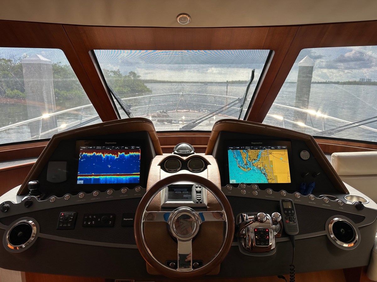 View from a boat cockpit with steering wheel and navigation screens.