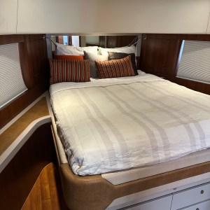 Boat cabin interior with bed, striped pillows, and wooden accents.