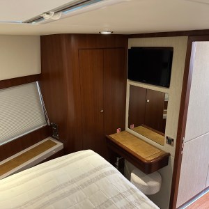 Cozy cabin room with bed, TV on wall, small desk below mirror, and closed window blinds.