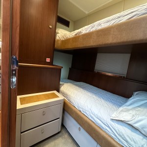 Small room with two bunk beds, wooden cabinets, and carpeted floor.