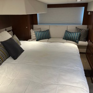 Cozy bedroom with a large bed, striped pillows, a sofa, and a TV cabinet.