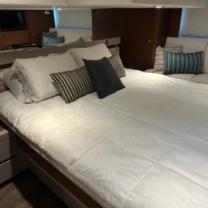 Spacious bedroom with large bed, striped pillows, and wooden walls, featuring a wall-mounted TV.