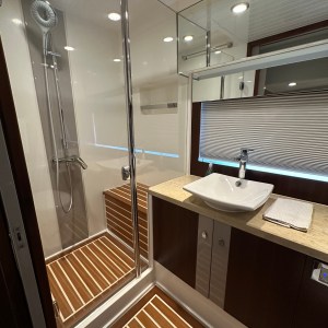 Modern bathroom with wood flooring, shower, sink, and mirror.