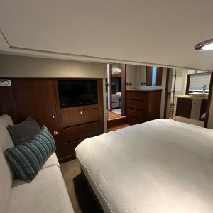 Cozy bedroom with bed, sofa, TV, and wooden cabinets on luxury yacht.