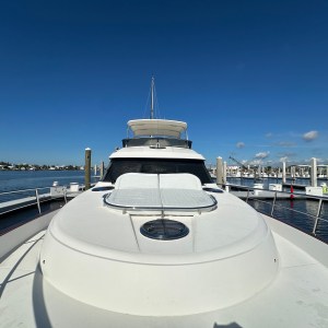 View of a yacht's deck and helm, docked at a sunny marina with clear skies.