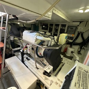 Interior of a boat engine room with an engine, control panel, and fire extinguisher.