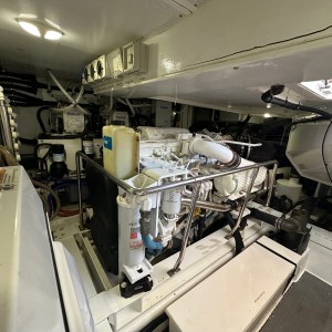Engine room with machinery, pipes, and cables inside a well-lit compartment.