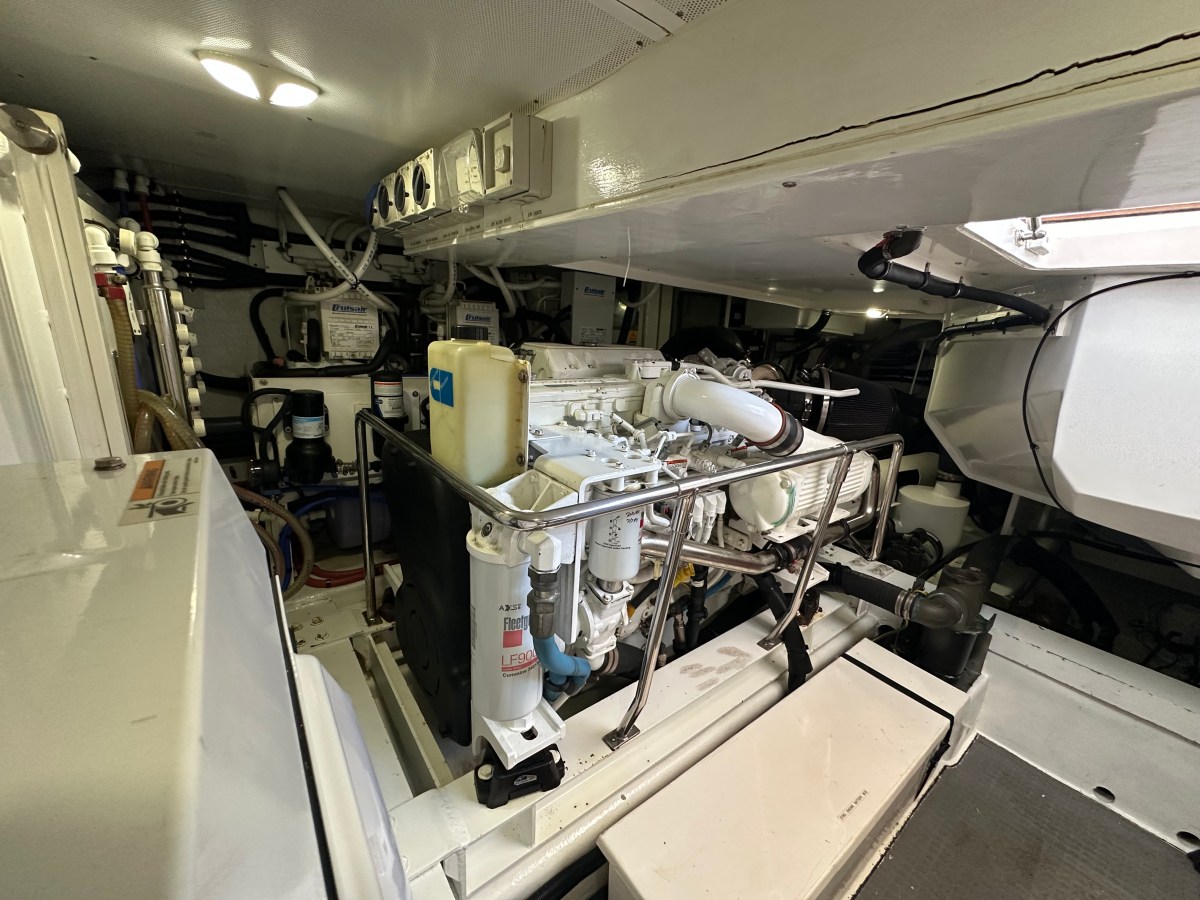 Engine room with machinery, pipes, and cables inside a well-lit compartment.