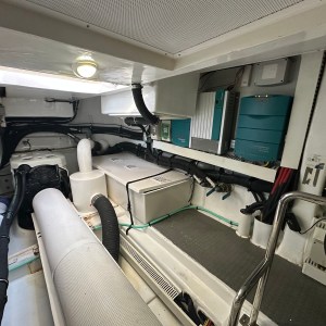 Interior of a boat engine room with various pipes, tanks, and machinery.
