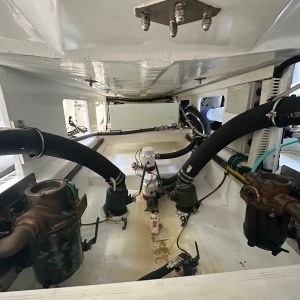 Engine compartment with hoses, pumps, and metal components inside a boat.