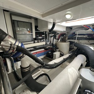 Interior of a boat engine room with pipes, wires, and electrical panels.